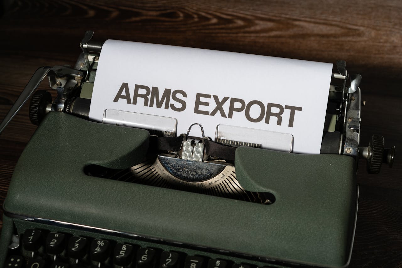 services-04 Close-up of a vintage typewriter with paper showing the text 'ARMS EXPORT'.